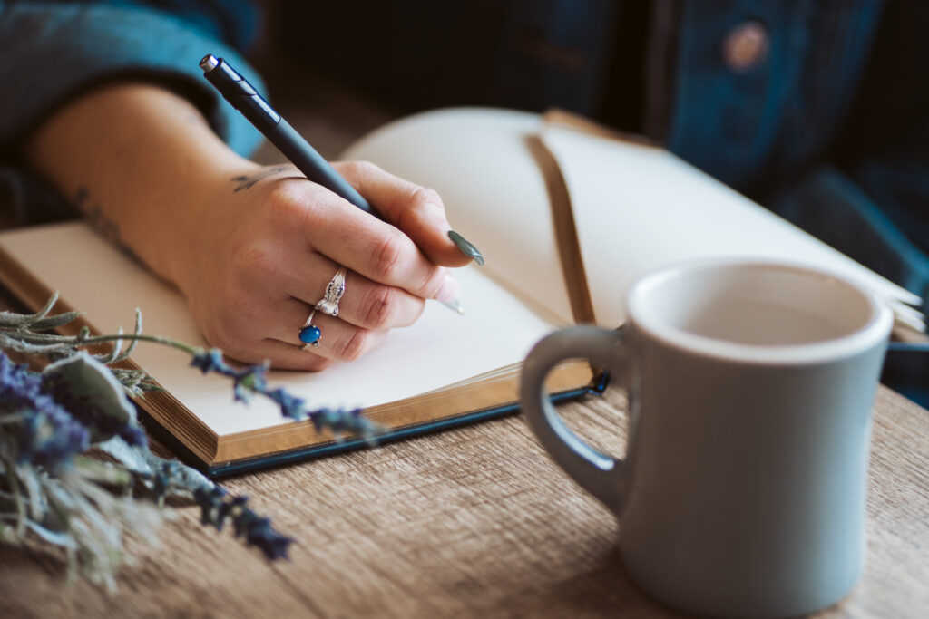 Hand,Writing,In,Journal,With,Coffee,Mug